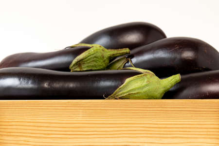fresh eggplants in crate isolated on white, wooden box with vegetablesの写真素材