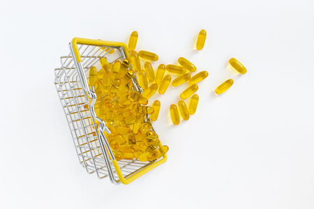 fish oil pills in shopping basket isolated on white background, close up of food supplement oil filled capsules suitable for fish oil, omega 3, omega 6, omega 9, health care conceptの写真素材