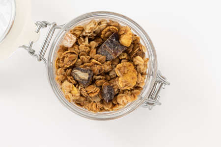 crunchy granola in glass jar isolated on white background, top view, healthy breakfast concept