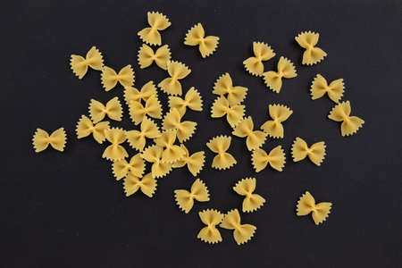 raw pasta farfalle with on black background, top view of italian cuisine ingredientの写真素材