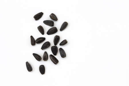 black sunflower seeds isolated on white background with copy space for text, top view of pile of roasted unpeeled seedsの写真素材