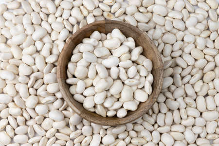 background of many grains of dried beans top view, white beans in wooden bowl, food background close...