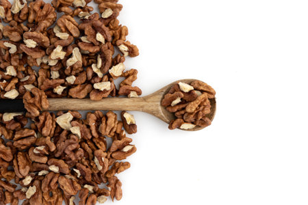 peeled halves of walnuts in spoon on heap isolated on white background, frame of nuts with copy...