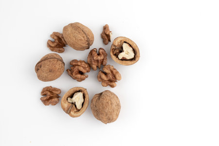 heap of walnuts isolated on white background, whole and cracked walnut, top view