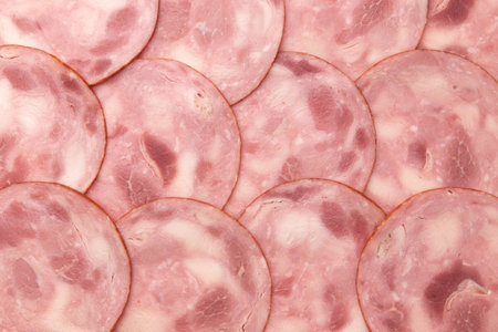 background of round pieces of ham close up, many slices of pork ham cut laid out to create layout,...