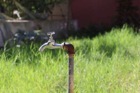 Photo of an outdoor water tap in nature background. Outdoor faucet in the garden.の写真素材