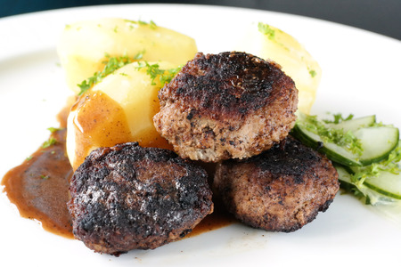 Swedish meatballs with potaoes and sauce on a white plate.