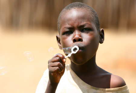 Portrait of African kid playing a bubbles. Editorial use onlyのeditorial素材