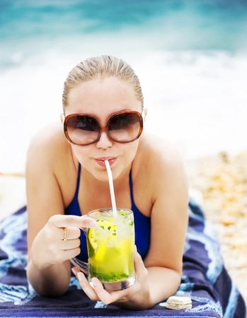 Portrait of a happy young woman drinking cocktail on the beach の写真素材