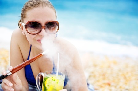 Portrait of a happy young woman drinking cocktail on the beachの写真素材