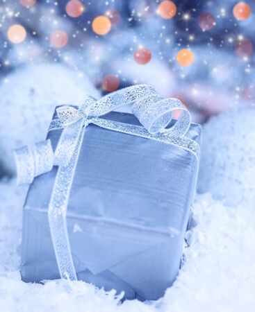 Winter holiday background with blue present gift box, silver ribbon ornament & Christmas snow decorationの写真素材