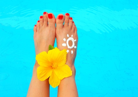 Beautiful female legs with flower in the pool conceptual image of vacationの写真素材