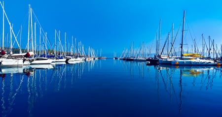 Yacht port over blue nature scene, row of luxury sailboats reflected in water の写真素材