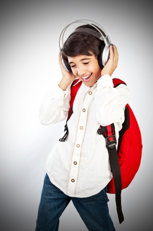 Pretty teen boy enjoying music, holding head with headphones, expressing pleasure and having fun, singing a songの写真素材