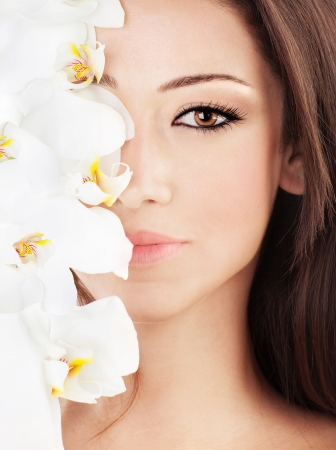 Closeup on beautiful face with white orchid flower, perfect clean skin, young female portrait, beauty and spa concept