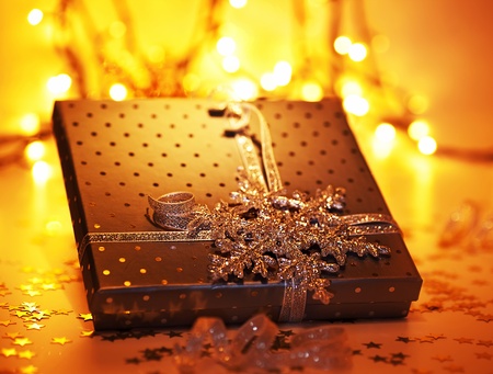 Golden gift box, Christmas ornament and winter holidays decoration over blur bokeh tree lights,...