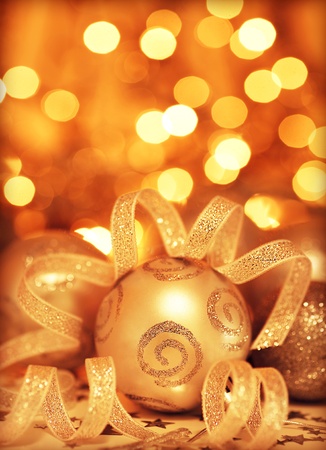 Golden baubles Christmas tree ornament, winter holidays decoration, ornamental decorative border, toys over gold background with magic glowing blur bokeh lights, new year eveの写真素材