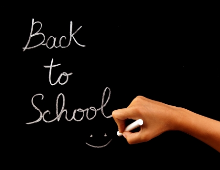 Handwriting phrase "back to school" on blackboard in classroom, conceptual image of school time, teacher arm holding chalk and writing word, education and knowledge conceptの写真素材