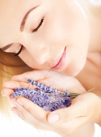 image of beautiful girl smell purple lavender flowers, closeup portrait of cute woman with closed eyes and holding sea salt and violet flower in hands, pretty female with clean skin, spa conceptの写真素材