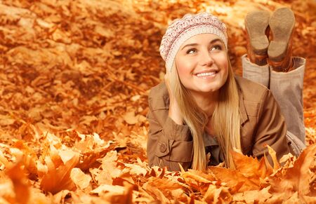 Photo of pretty girl lying down on the ground covered dry autumnal foliage