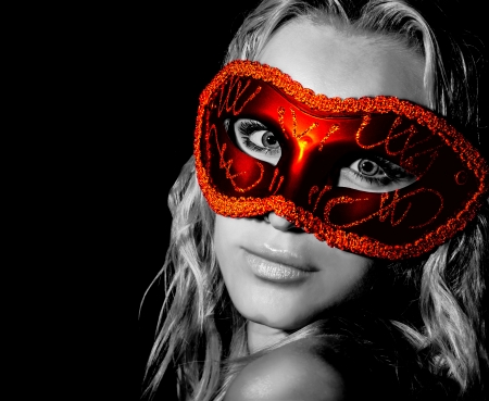 Mysterious woman wearing decorative face mask, girl at holiday party celebration, sexy female in red light isolated on black background, New Year and Christmas fashion costume, black and whiteの写真素材