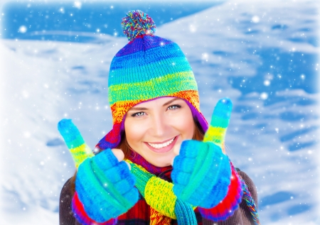 Colorful thumbs up of a happy smiling girl wearing winter clothesの写真素材