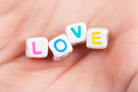 Photo of game cubes with love word on woman's palm, romantic holiday, affection symbol, romance relationship, colorful letters in the man's hand, Valentine day, happiness conceptの写真素材