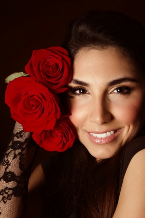 Picture of attractive female with beautiful red roses isolated on black background, sexy arabic girl with cute romantic gift, Valentines day, perfect makeup, glamorous woman, elegance conceptの写真素材
