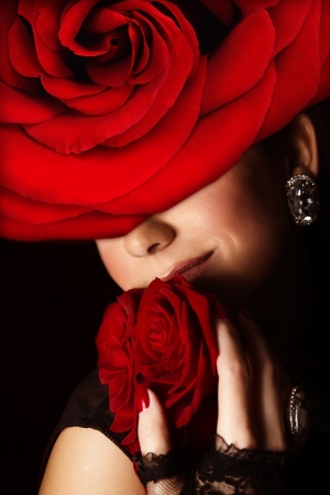 Photo of pretty arabic woman wearing stylish red floral hat, closeup portrait of attractive female with fresh roses bouquet, romantic gift for Valentine day holiday, beauty salon, fashion conceptの写真素材