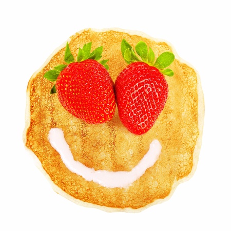 Tasty fried pancake with beautiful smiley face isolated on white background, red strawberry eyes, white creamy mouth, sweet dessertの写真素材