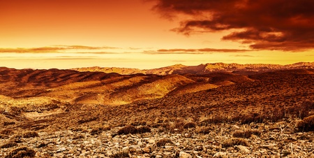 Photo of beautiful red dramatic sunset in desert, sandy mountains landscape, summer season, travel and tourism conceptの写真素材