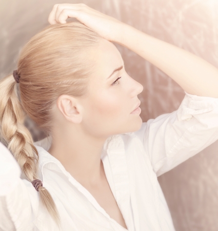 Closeup portrait of seductive woman isolated on tender pink background, profile of cute blond girl with pigtail hairstyle, beauty conceptの写真素材