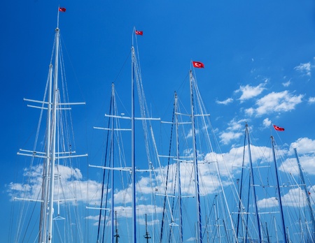 Yachts mast with turkish flags on blue sky background, sailing cruise to the Turkey, luxury summer vacation, relaxation in the sea, joy conceptの写真素材