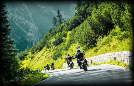 Group of moto bikers on mountainous highway, riding on curve road pass across Alpine mountains, extreme lifestyle, freedom conceptの写真素材
