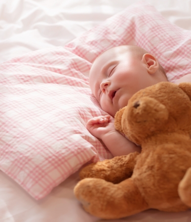 Little baby asleep with plush bear toy, newborn girl napping in the bed at home, child care, closed eyes, healthy lifestyle, happy childhood conceptの写真素材