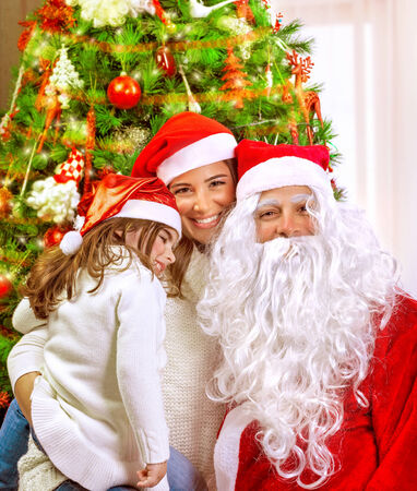 Christmas party, happy family at home celebrating New Year, mother with daughter and Santa claus near Xmas tree, happiness conceptの写真素材