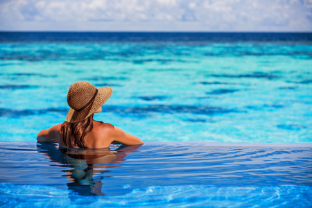Having fun on beach resort, back side of sexy woman enjoying seascape from the pool, luxury summer...