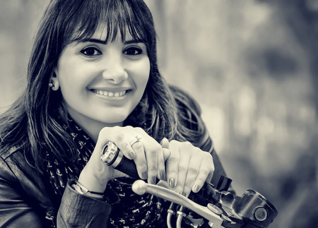 Closeup portrait of beautiful woman sitting on motorcycle, resting outdoors after long extreme bikers tour, black and white photo, travel and vacation conceptの写真素材
