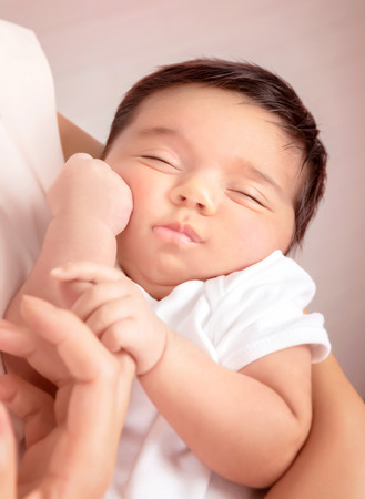 Cute sleeping baby portrait, mother holding on hands sweet newborn toddler, happy childhood, new life conceptの写真素材