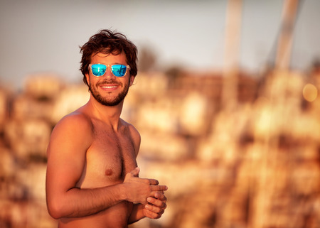 Portrait of handsome guy on the beach in mild yellow sunset light, perfect athletic body, summer vacation on luxury sailboat
の写真素材