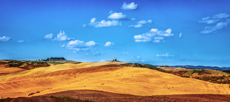 Beautiful autumnal landscape, dry golden hills with many haystack on it, panoramic farmland in Europe, harvest season conceptの写真素材