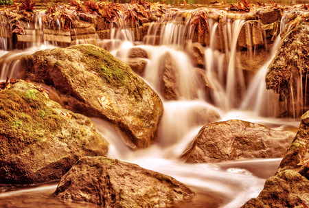 Beautiful waterfall landscape, wild river streaming through stones in mountainous forest, majestic scene, autumn nature conceptの写真素材