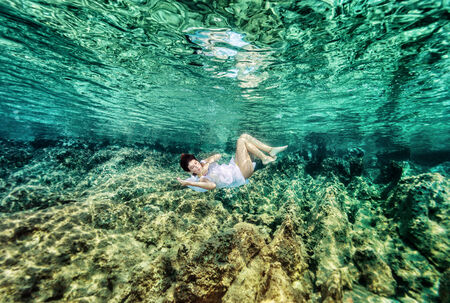 Dancing underwater, beautiful young female swimming in the sea near beautiful coral garden, active lifestyle, summer holidays and vacation conceptの写真素材