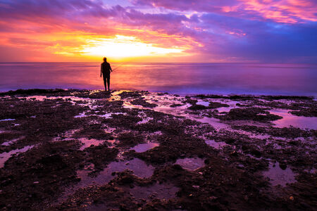 Silhouette of fisherman in amazing colorful sunset light, enjoying angling on beautiful coastline, recreation outdoors, favorite men's sportの写真素材