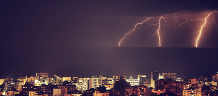 Lightning over night city, amazing dramatic landscape, bright powerful thunderbolt, stormy weatherの写真素材