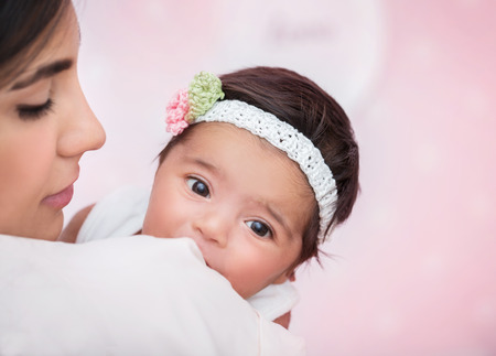 Closeup portrait of cute adorable little baby girl peeking over his shoulder mother, wearing nice...