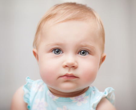 Closeup portrait of a beautiful little baby girl isolated on gray background, carefree childhood,...