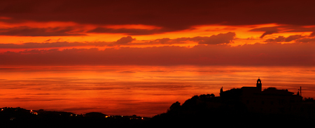 Silhouette of a little coastal town, church on the hill on sunset light, amazing panoramic view, stunning cityscapeの写真素材
