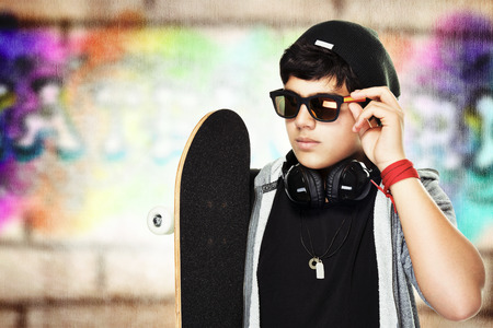 Portrait of a handsome skateboarder wearing sunglasses and stylish hat outdoors, active stylish teenの写真素材