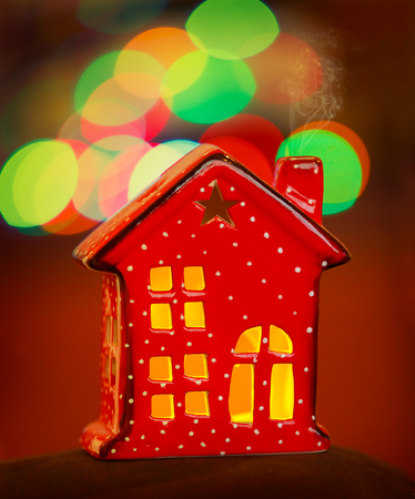 Beautiful Christmas decorations, cute little red decorative house over blurry lights background, festive Christmastime still lifeの写真素材